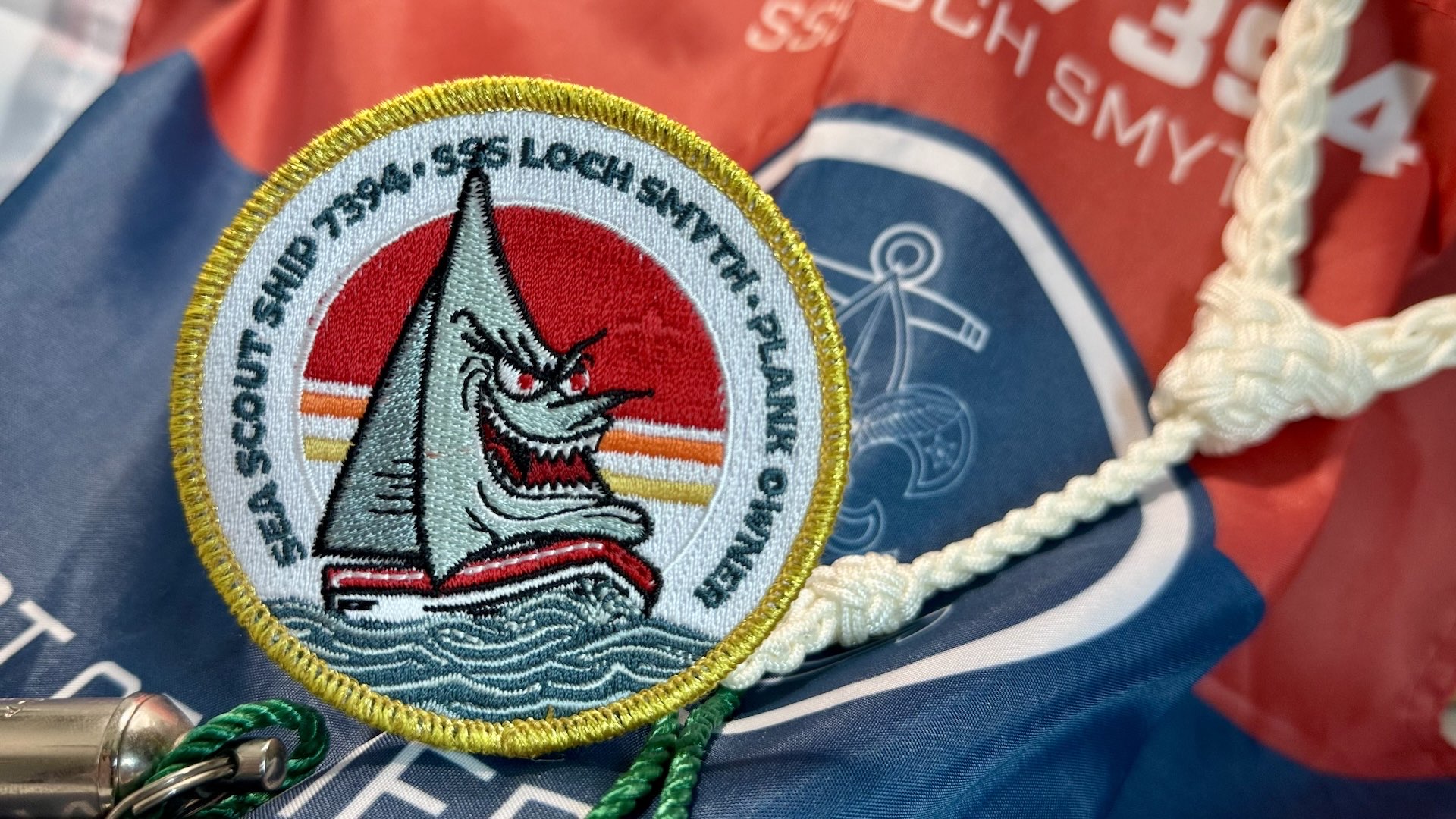 Photo of a Plank Owner patch displayed using the ship flag as a backdrop.